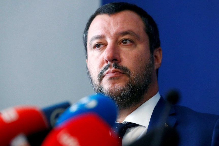 Matteo Salvini stands by a pack of microphones.