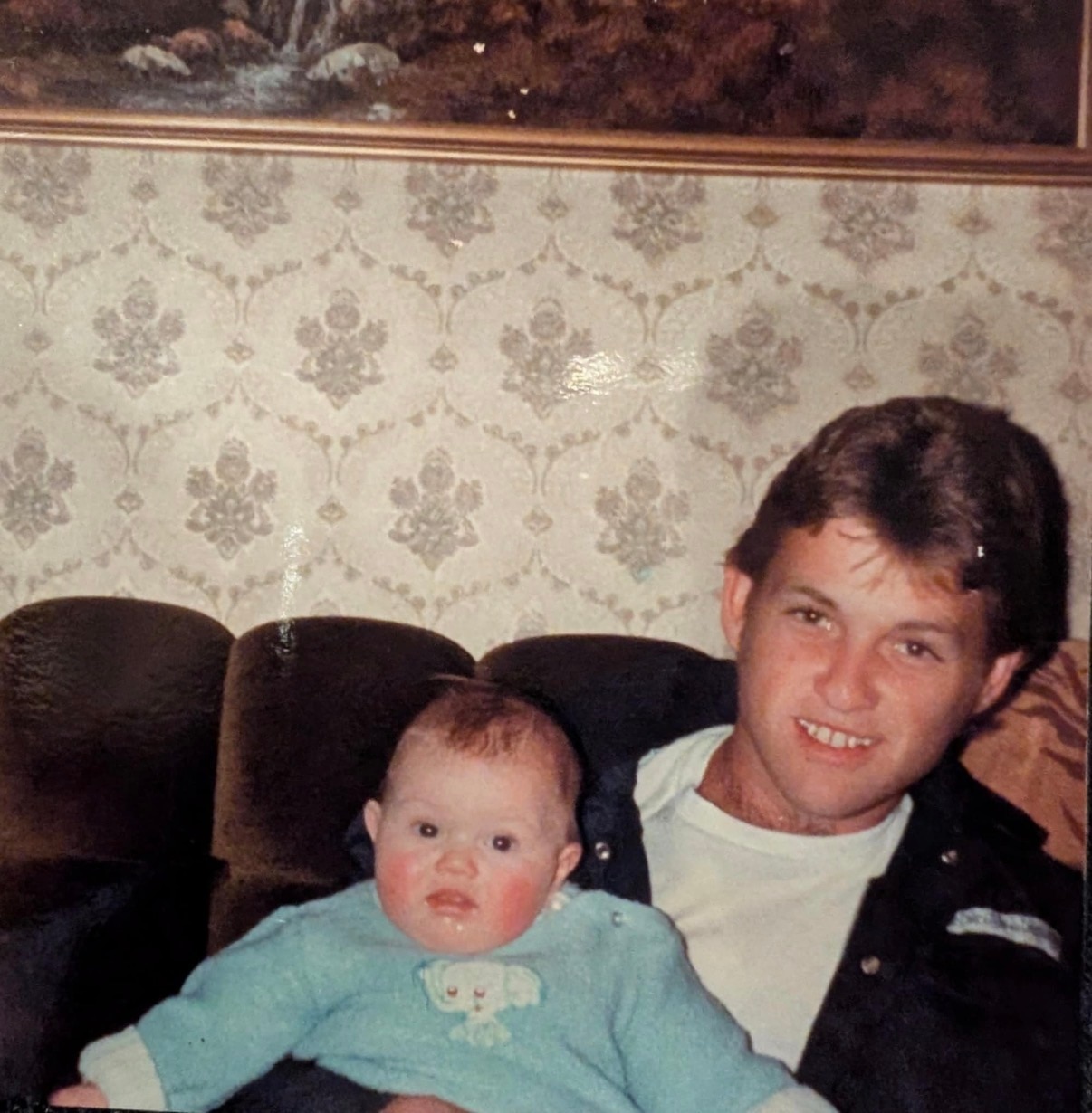 Old photograph of a man holding a baby and smiling at the camera.