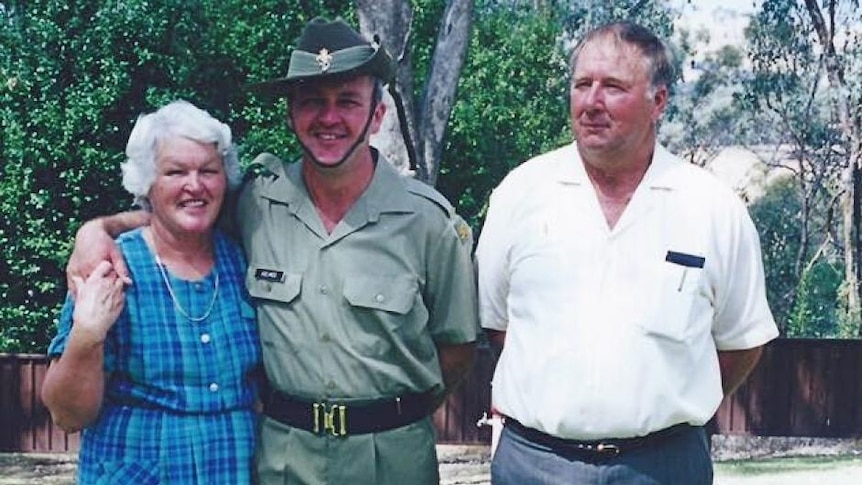 a woman and two men stand arm in arm posing for a photo