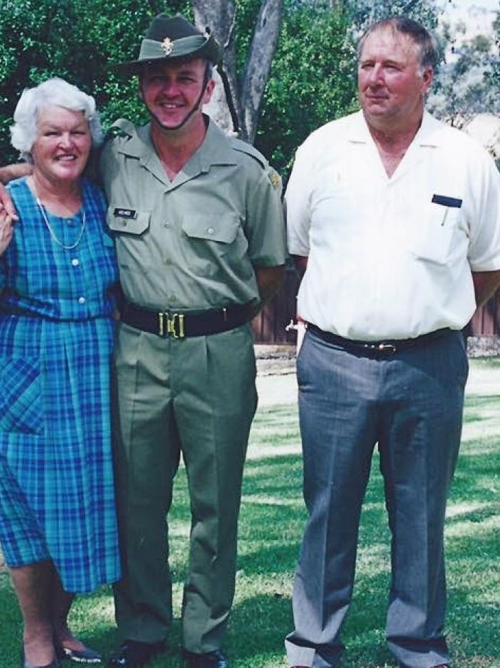 a woman and two men stand arm in arm posing for a photo