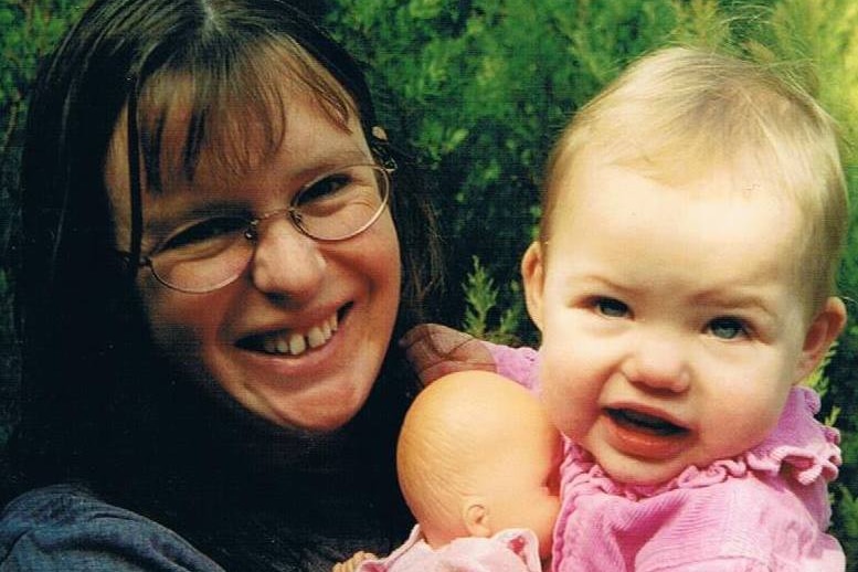 Nicola smiles, holding one of her kids as a baby.
