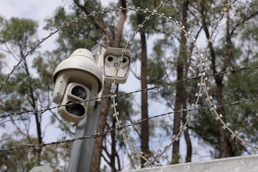 A security camera looks out over barbed wire at the AFTER facility.