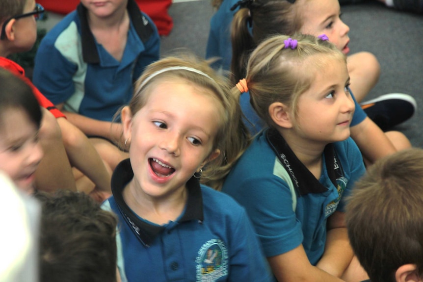 A young girl sits with classmates singing