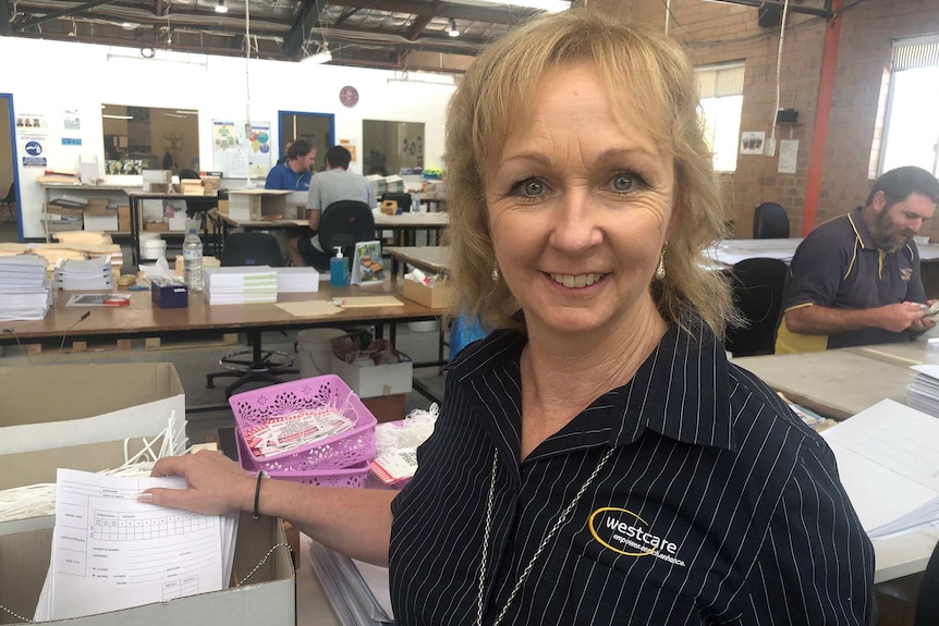 A med shot of a smiling woman posing for a photo in a Westcare workshop.