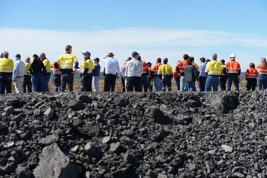 A crowd of people standing looking out onto a pit at Burton mine with coal in the forefront. 