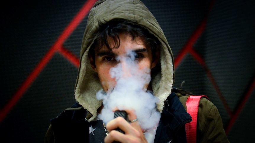 A man in a hoodie vapes