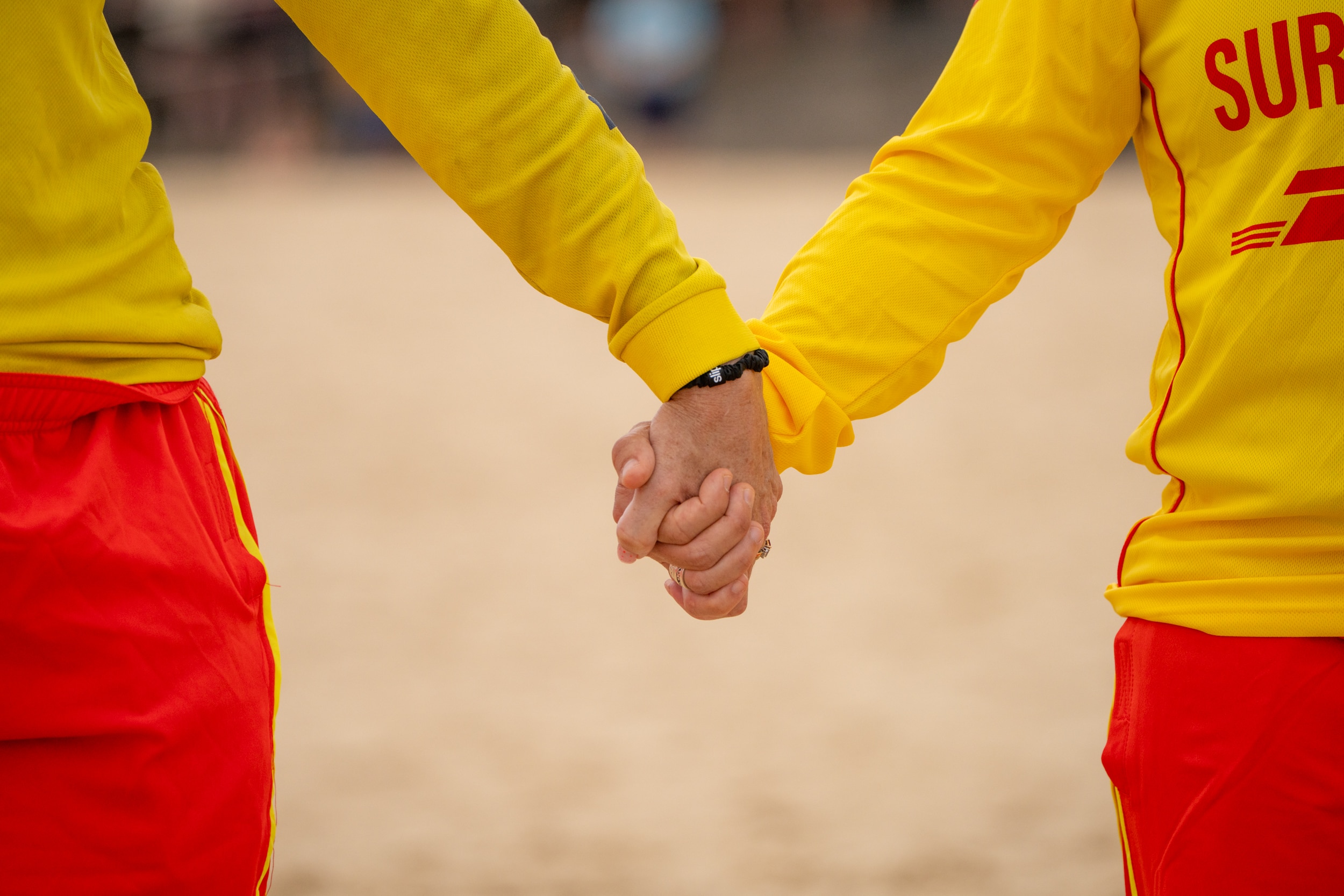 Dois salva-vidas de surf de mãos dadas na areia