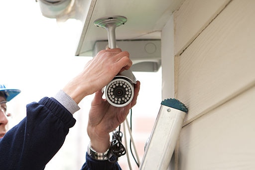 A man installs a security camera outside a home.