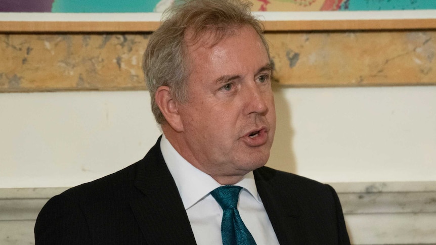 Kim Darroch gesturing in front of a microphone.