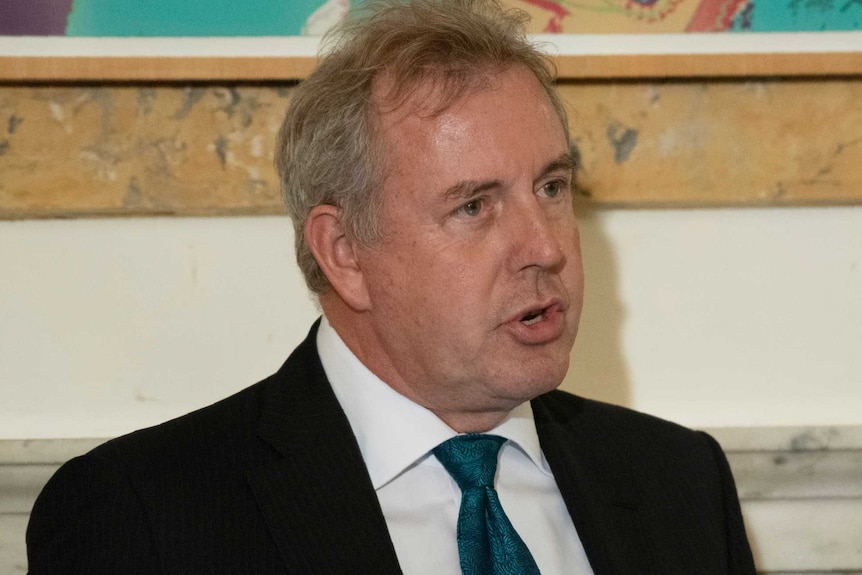 Kim Darroch gesturing in front of a microphone.