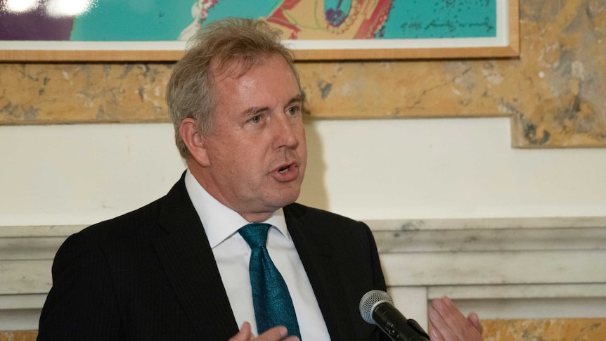 Kim Darroch gesturing in front of a microphone.