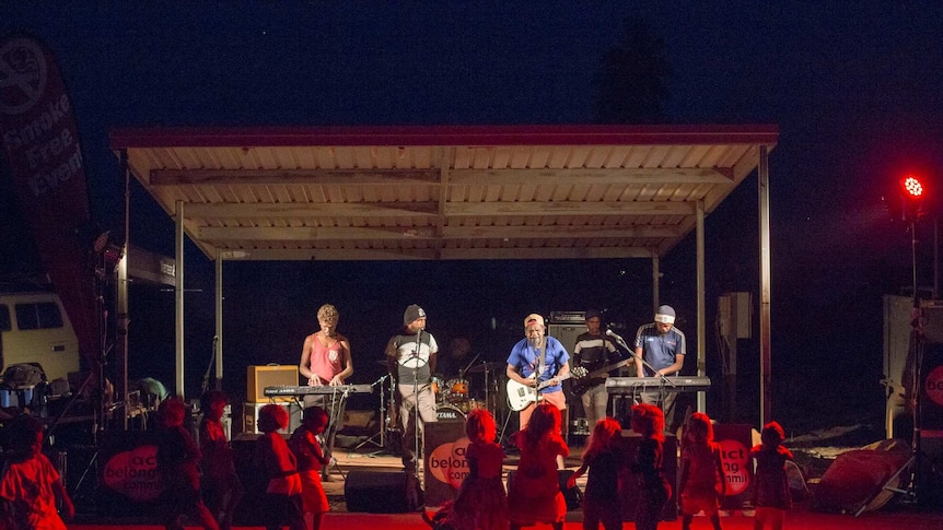 A community concert taking place in Kiwirrkurra. Children are dancing before a playing band.