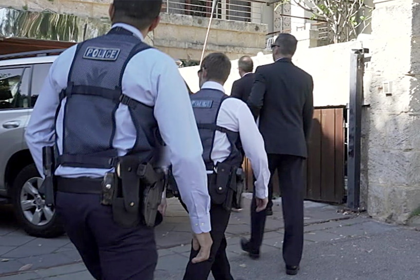 Police walk up to a fancy house.