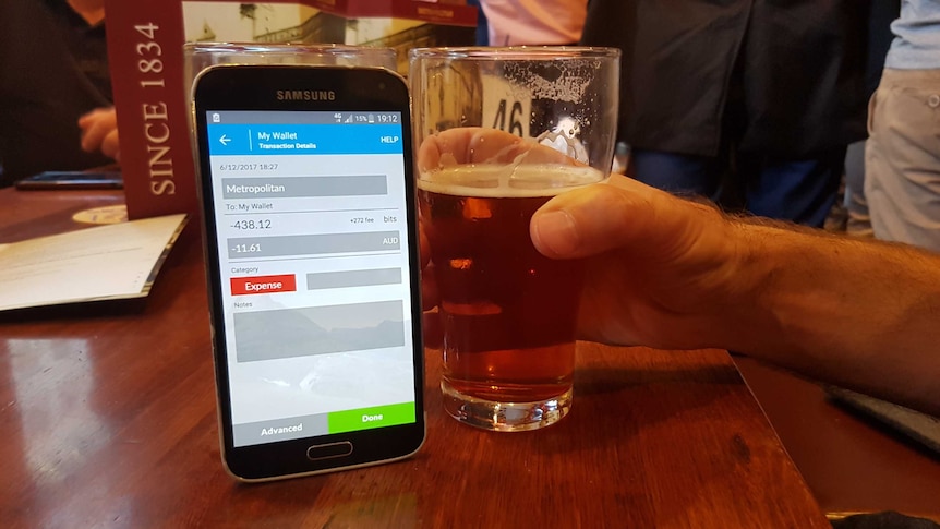 A customer pays for a glass of beer using bitcoin