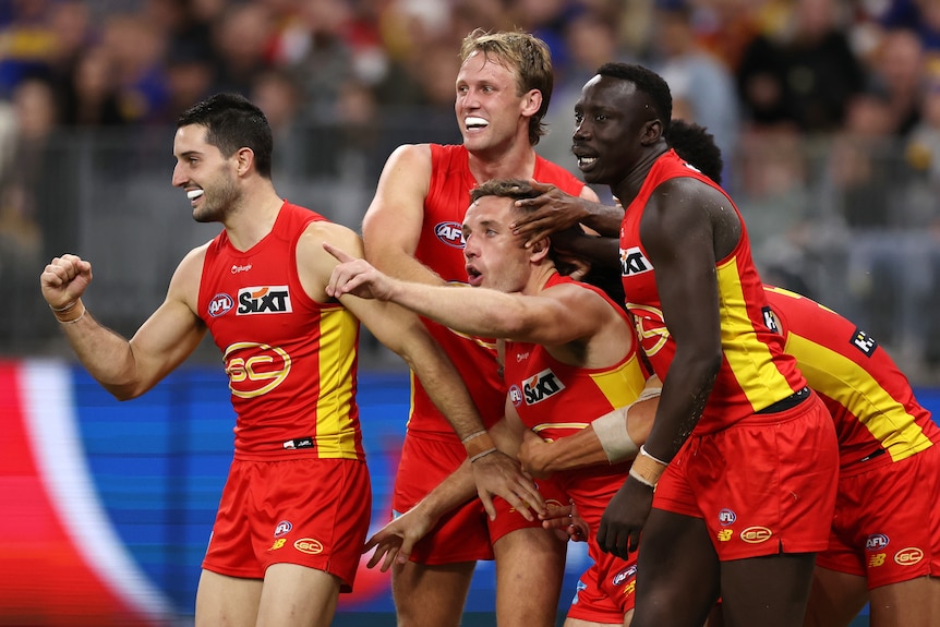 Gold Coast Suns players celebrate with James Tsitas after a goal