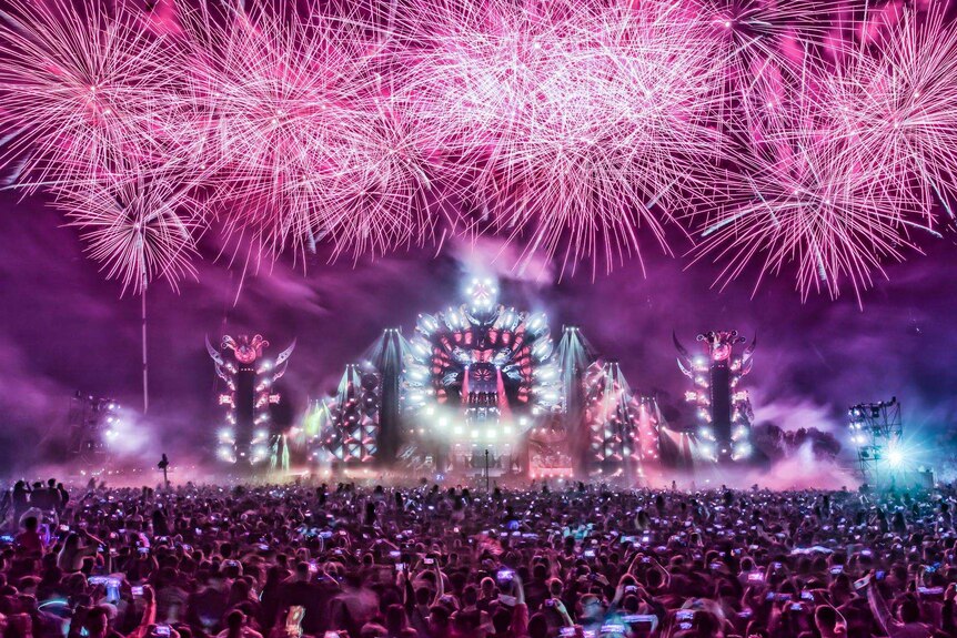 Fireworks over a stage in front of a crowd.