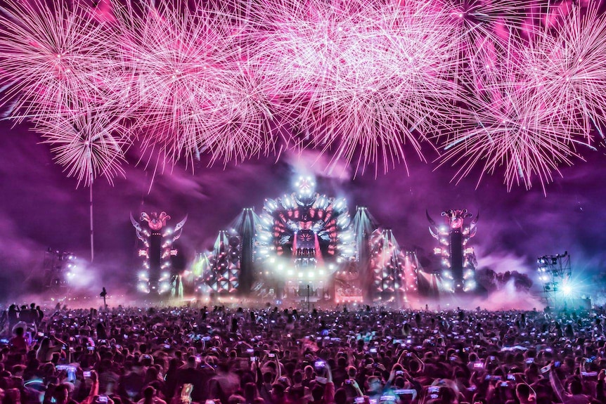 Fireworks over a stage in front of a crowd.