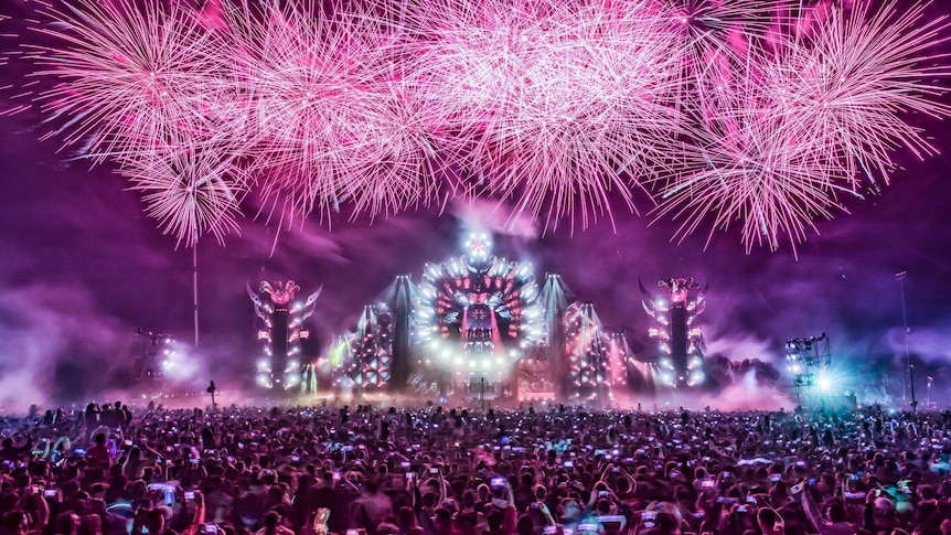 Fireworks over a stage in front of a crowd.