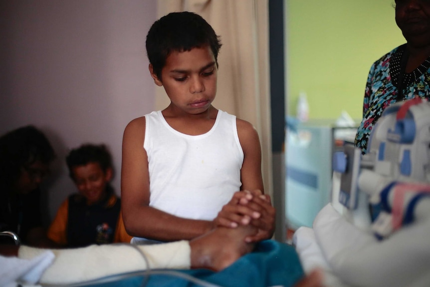 An Aboriginal boy massages a person's foot.