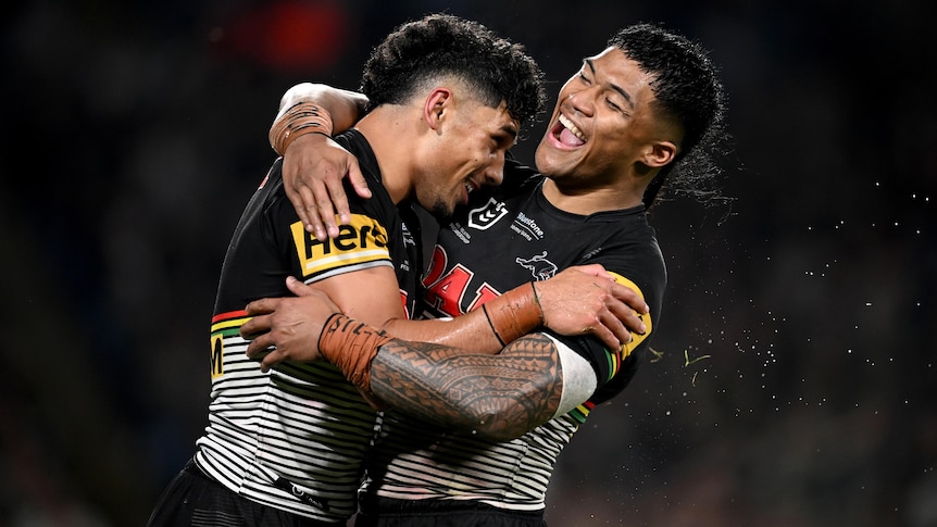 Two Penrith Panthers NRL players embrace as they celebrate a try.