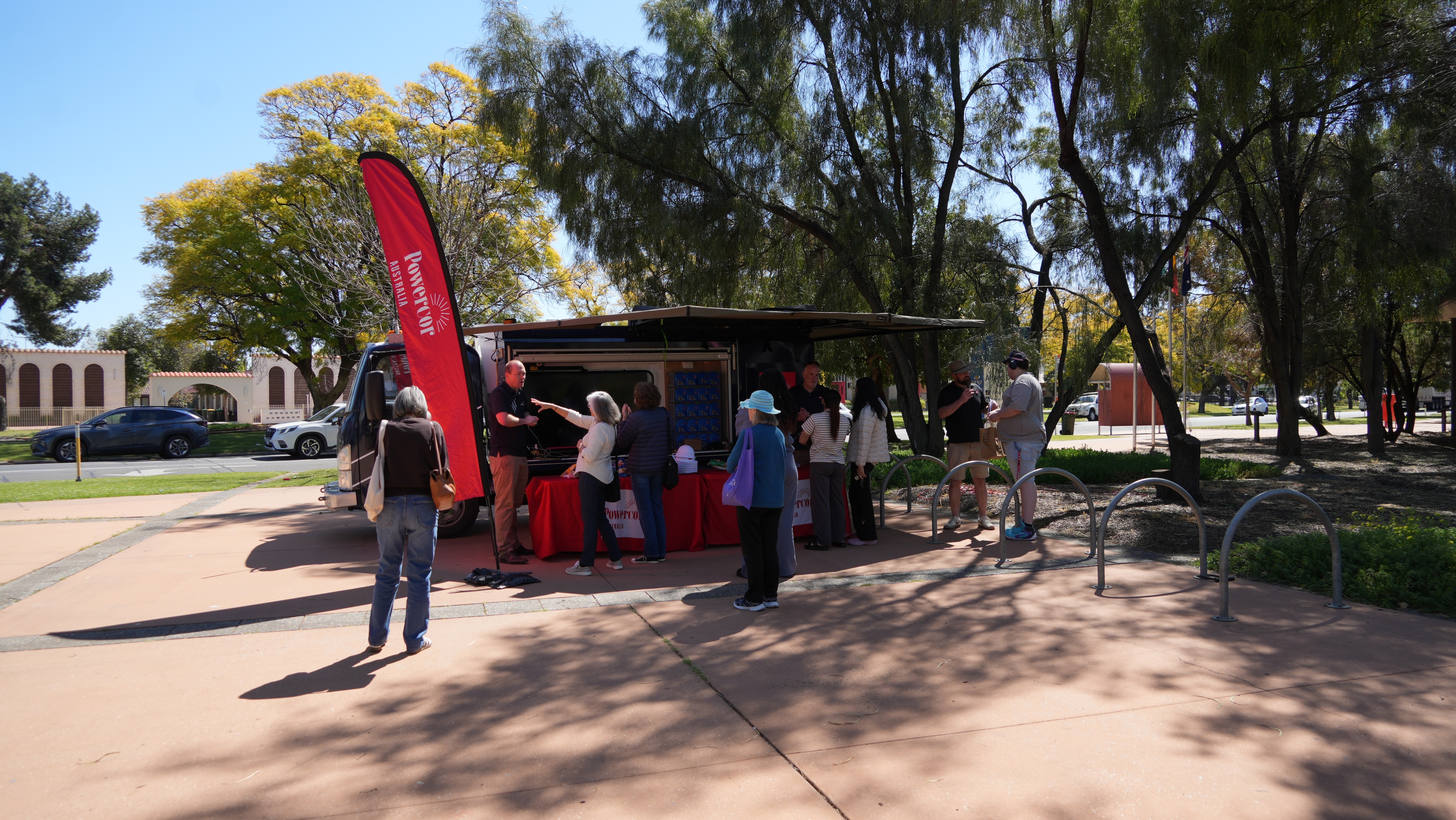 Van outside on concrete with red Powercor banners and Powercore staff speaking with civilians