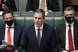 Jim Chalmers gives a speech in parliament as two MPS sit either side of him