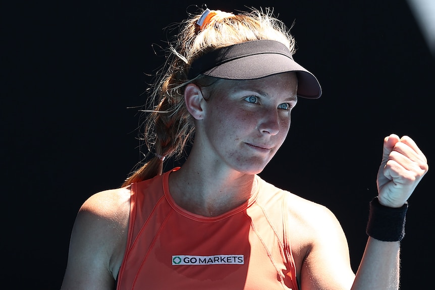 An Australian female tennis player raises her left fist as she celebrates winning a point.