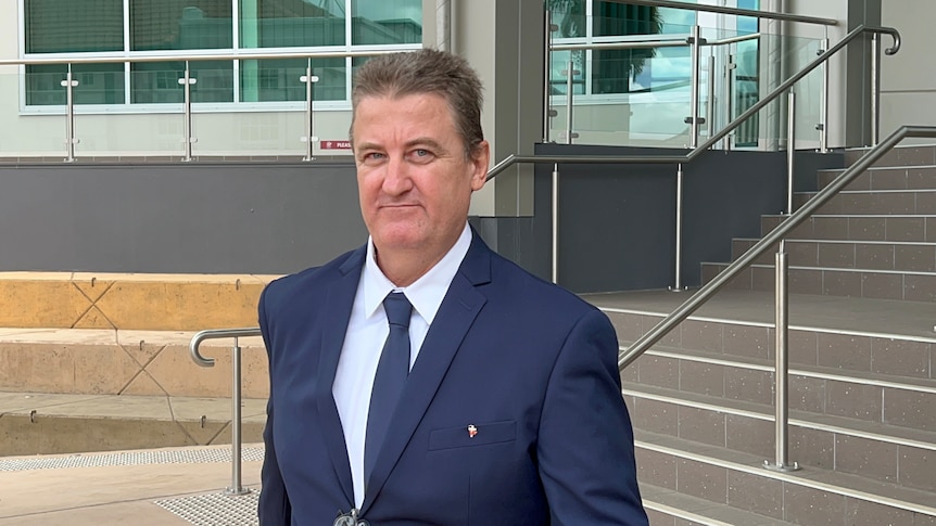 A man in a suit looking at the camera in front of some steps