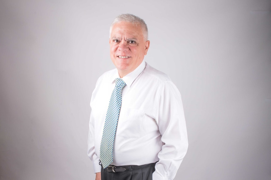 Studio portrait of man with white hair, white shirt and tie