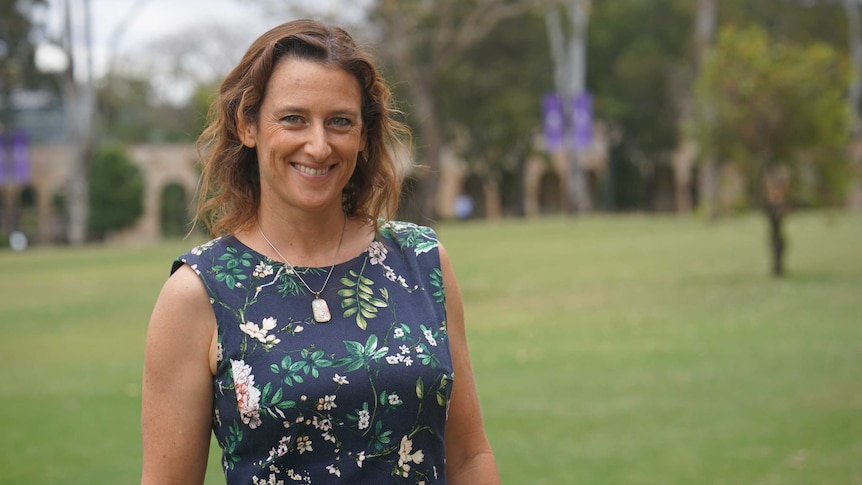 A woman outdoors smiling to camera.