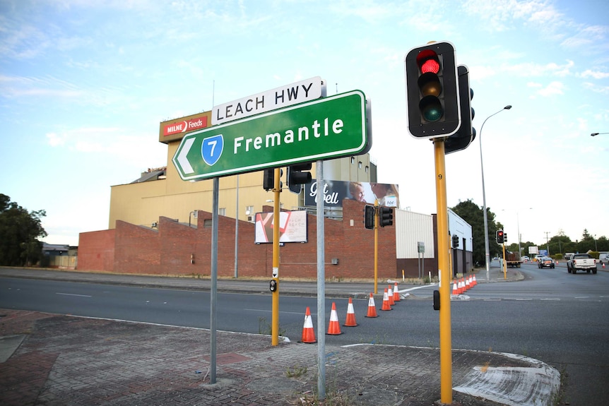 A street sign next to traffic lights on Leach Highway in Welshpool, with red traffic cones blocking the road.