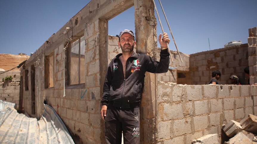 Abdo Kanaan stands in front of his partly demolished concrete block house