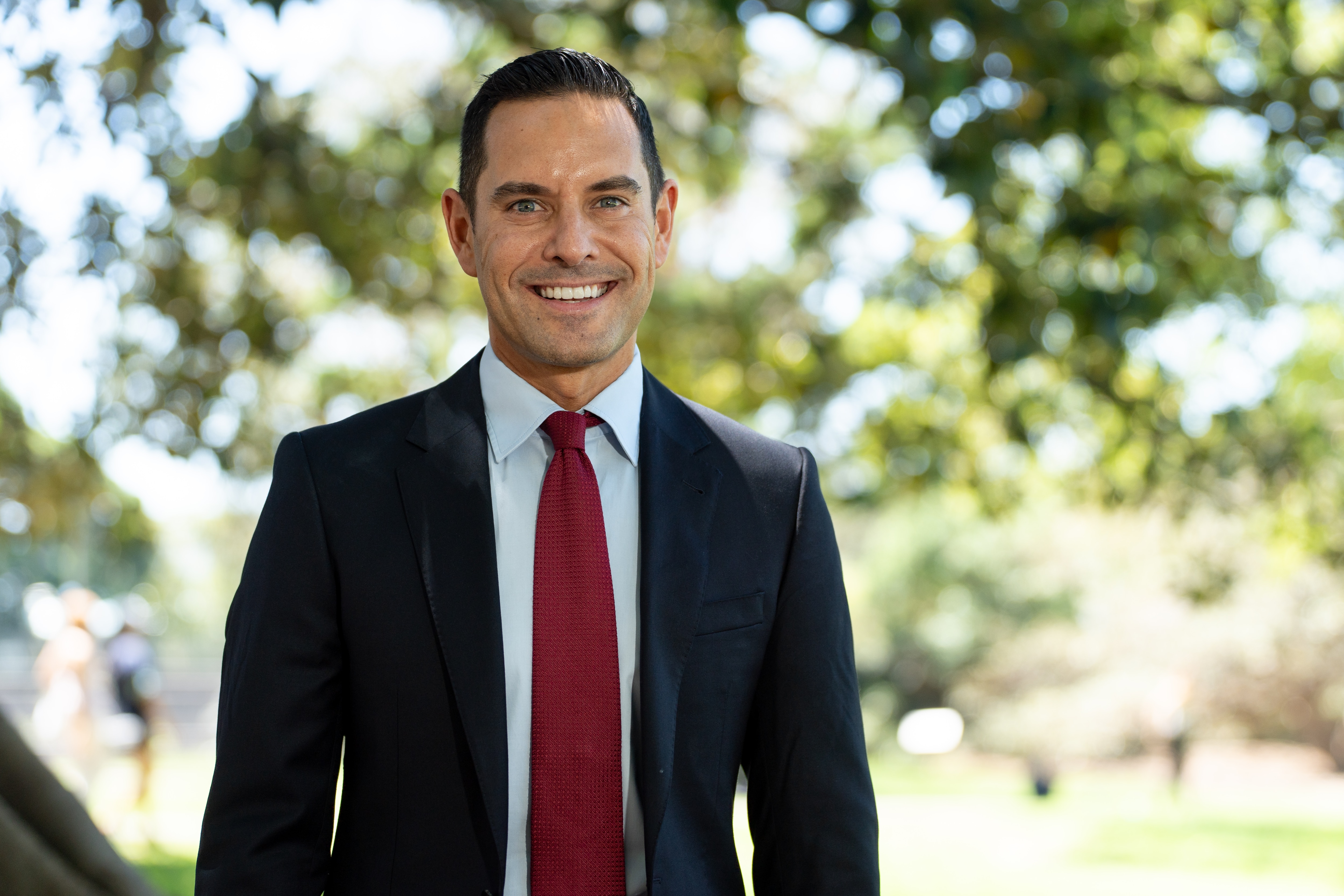 Alex Greenwich de terno e gravata vermelha