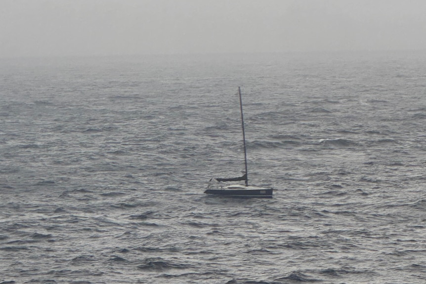 A yacht drifts on the sea, shrouded in fog.