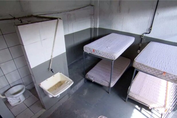 Two bunk beds and a sink in a prison cell.