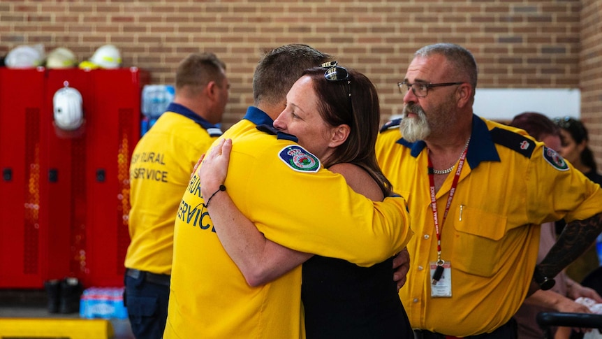 A volunteer firefighter hugs a woman in relief centre