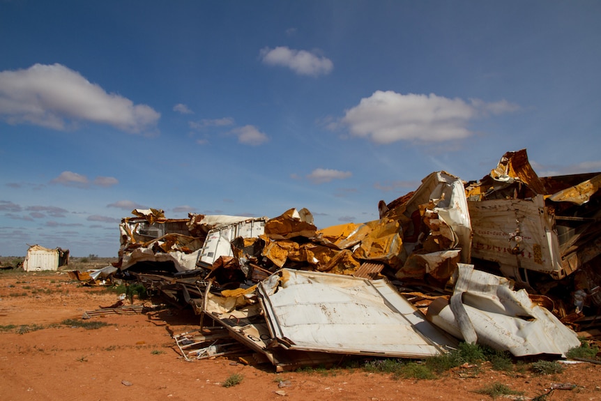 A pile of torn-apart, rusted freight containers