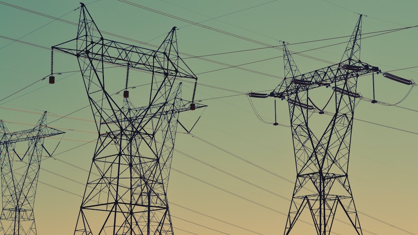 Black transmission towers under sunset sky.