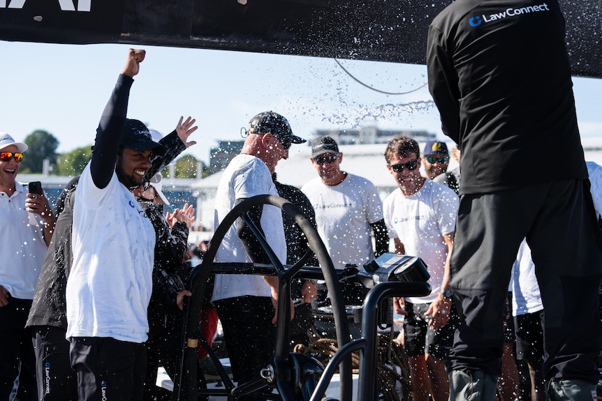 LawConnect crew members pump their fists into the air and celebrate with a spray of champagne.