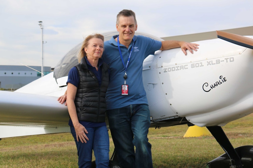 Steven and Christine Mogg in front of a small plane.