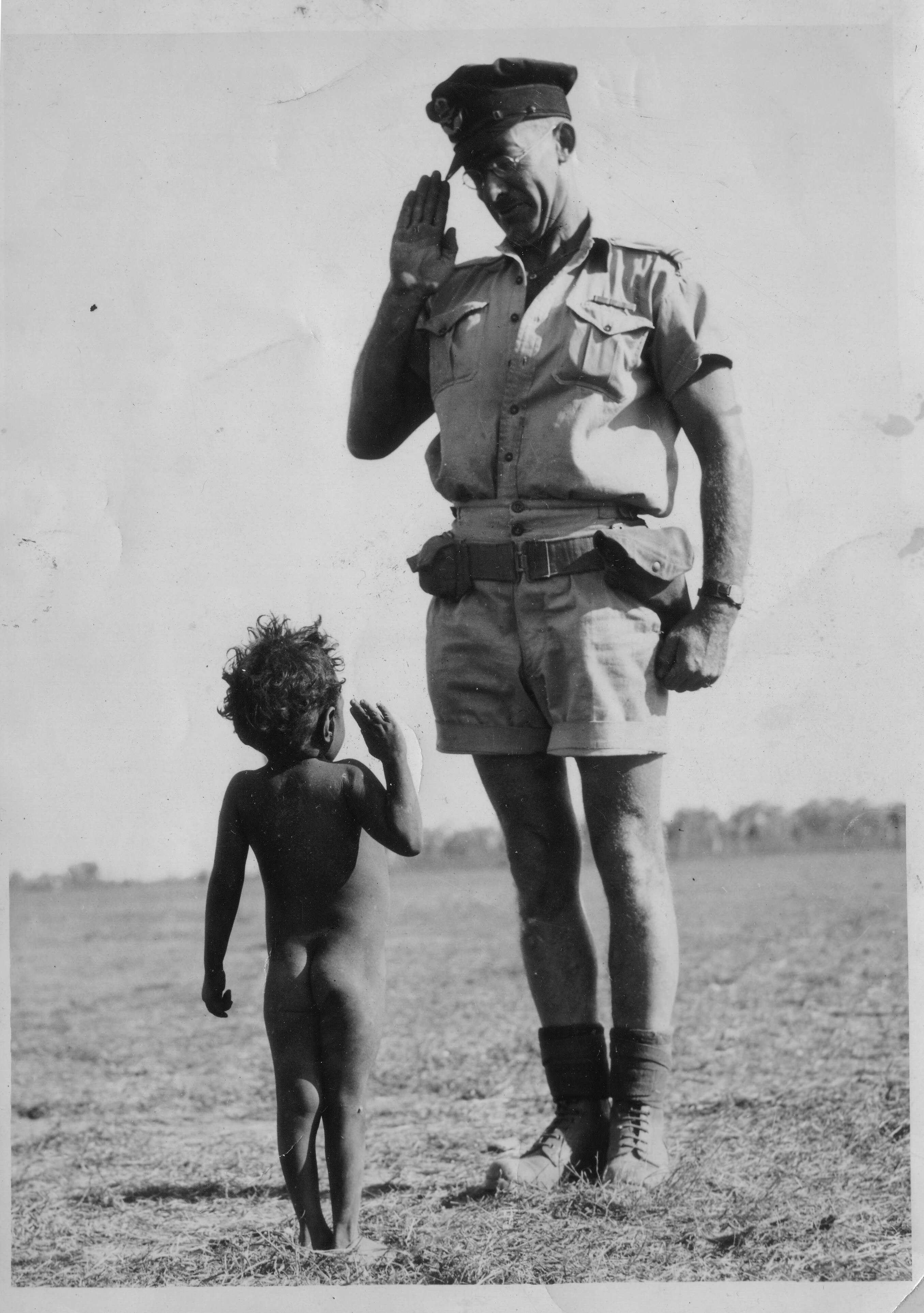 Toddler saluting an officer. Deep shadows.