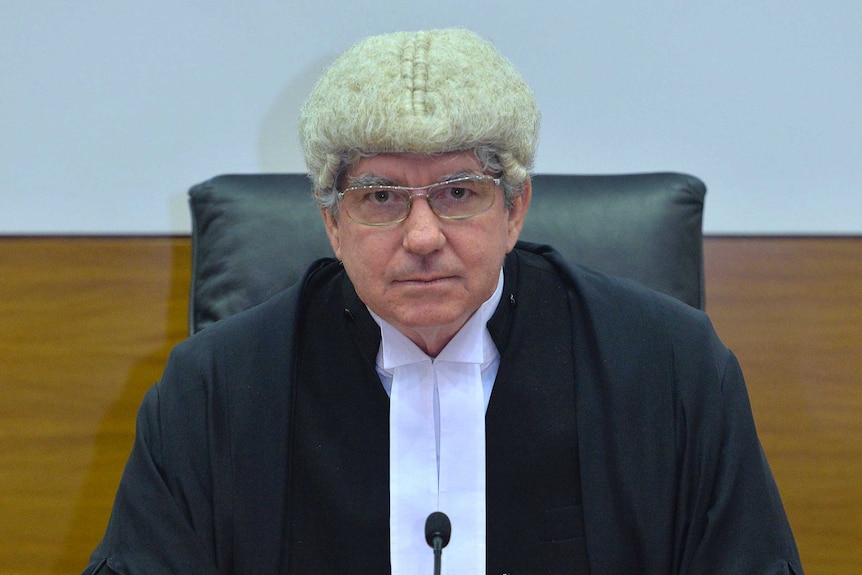Chief Justice Michael Grant wearing in his judge attire sitting at a court bench.