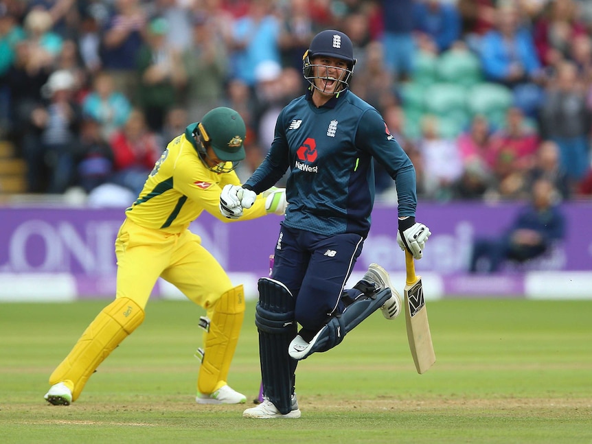 Jason Roy runs away, smiling with his bat in his hand with Tim Payne in the background.