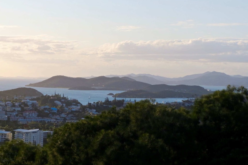 At sundown, you look down on gentle hills set between turquoise waters with the Noumea skyline in the distance.