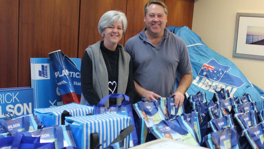 A man and a woman stand in an office surrounded by Liberal party resources and banners.