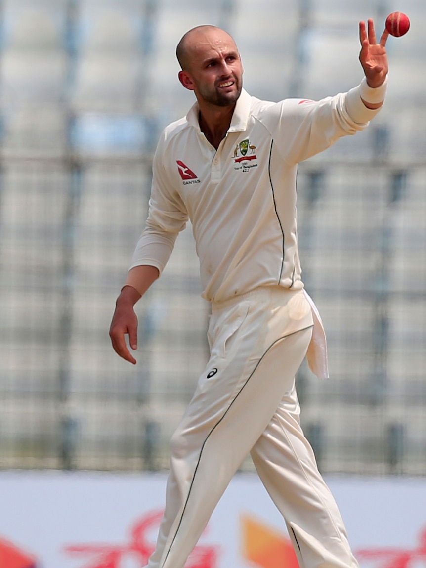 Nathan Lyon catches a ball one-handed before bowling against Bangladesh.