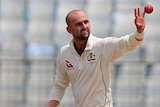 Nathan Lyon catches a ball one-handed before bowling against Bangladesh.