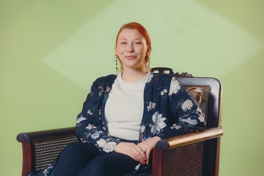 Amanda Morgan sits in a chair with a blue floral cardigan on and grey shirt.