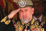 The former Malaysian sultan wearing a traditional outfit and saluting.