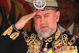 The former Malaysian sultan wearing a traditional outfit and saluting.